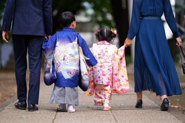 秋の神社の参道を歩く七五三の子どもの後ろ姿